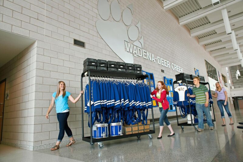 Students rolling a Wenger Rack 'n Roll Garment Cart with band uniforms through school hallway