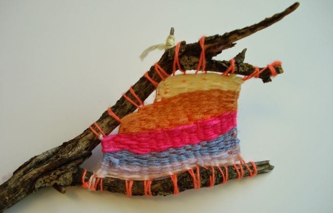 Forked stick with yarn stripes woven between the twigs
