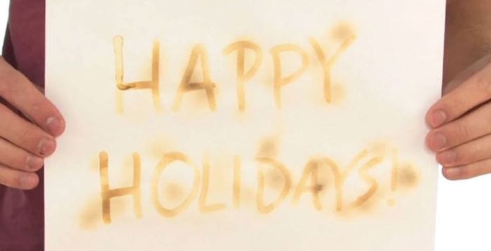  レモン汁で書かれた「Happy Holidays」の紙を持つ3年生の科学生