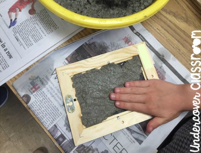 Estudiante de ciencias de tercer grado presionando la pulpa de papel en un marco de fotos de madera