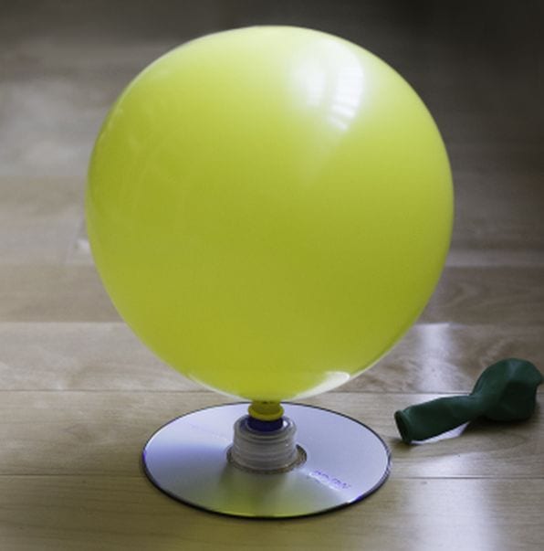 Inflated yellow balloon attached to a CD by a bottle cap
