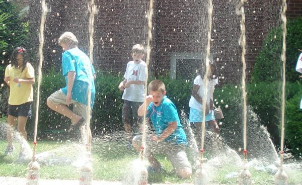 Fourth grade science students looking on in amazement as diet soda shoots high into the sky from bottles