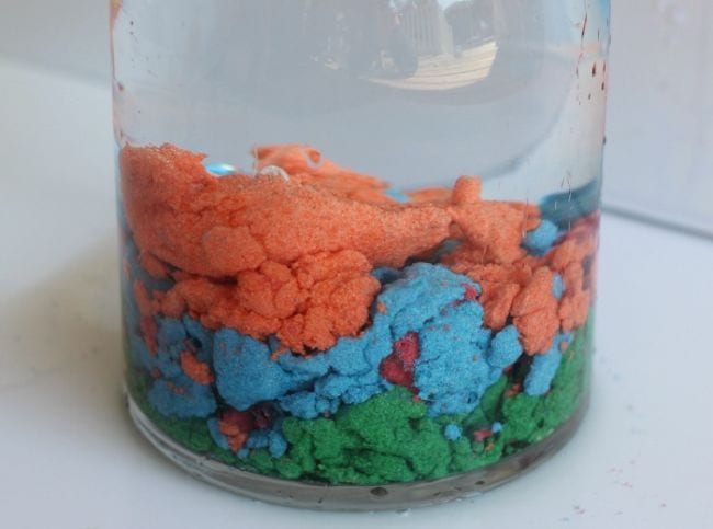 Glass jar filled with wet sand in various colors