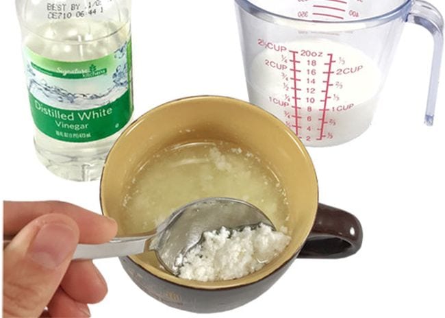 Student scooping plastic fragments out of a mug next to bottle of vinegar and measuring glass of milk (Easy Science Experiments)