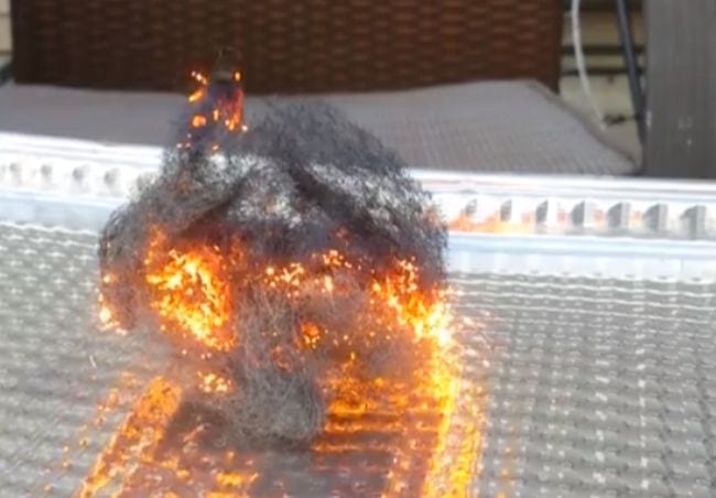 Steel wool sitting in an aluminum tray. The steel wool appears to be on fire.