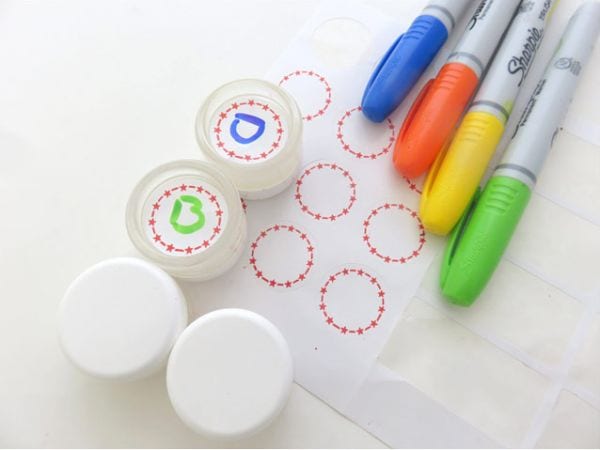 Small containers of homemade lip balm, with paper labels and colorful Sharpie markers