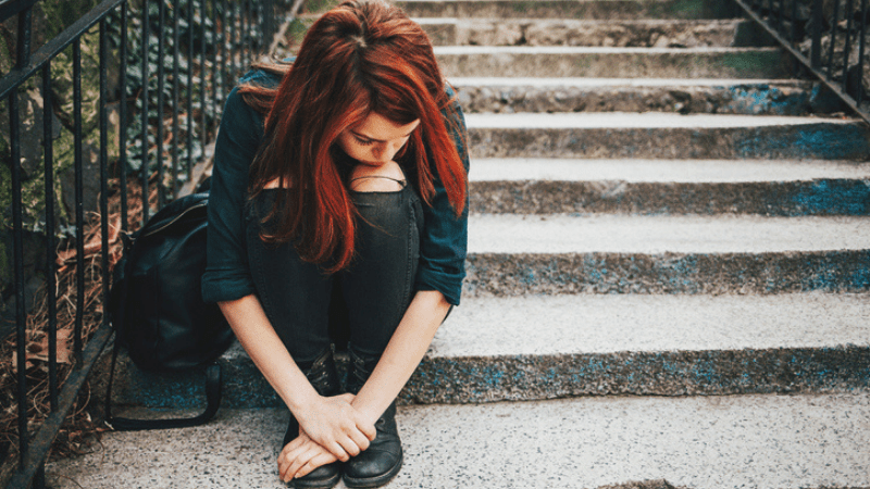 depressed teen girl sitting on steps outside
