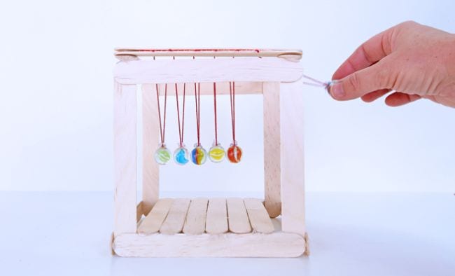 Newton's Cradle built of wood craft sticks, yarn, and marbles