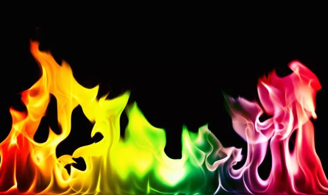Flames of orange, yellow, green, pink, and red against a black background