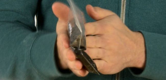 Man rubbing hands together with plastic bag of black liquid in between