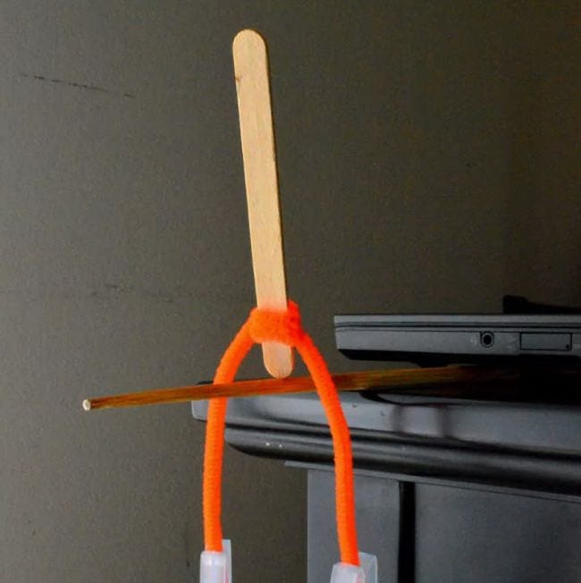 Wood craft stick balanced on end on a pencil, with orange pipe cleaner twisted around it (Eighth Grade Science)