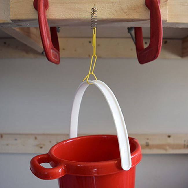 Red plastic bucket suspended by several paper clips from a spring on a hook (Eighth Grade Science)