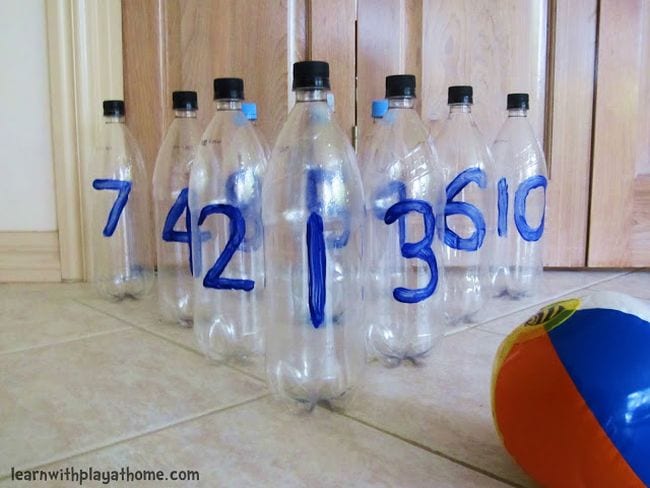 Plastic bottles with numbers set up like bowling pins with a beach ball (Active Math Games)