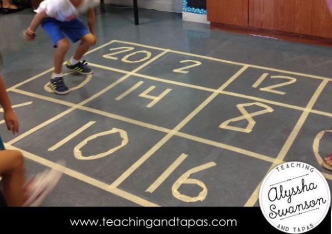 Student jumping on a large number grid made of masking tape on the floor (Math Facts Practice)