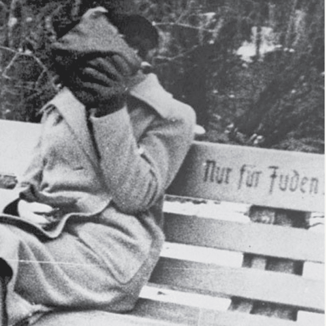 Black and white photograph of a woman sitting on a bench with the words "Only for Jews" written on it in Austria in 1938
