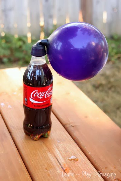 a purple balloon inflating on top of a coca cola bottle