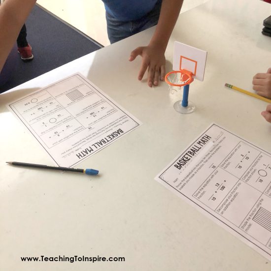 desktop with a tiny basketball hoop, fraction worksheets, a pencil and a student's hand