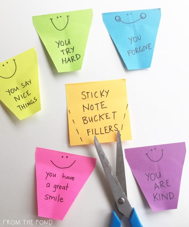 Square sticky notes trimmed to resemble a bucket shape with kind sentiments written on them