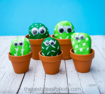 tiny clay pots with rocks painted green to look like cactus plants and googly eyes glued on to each plant