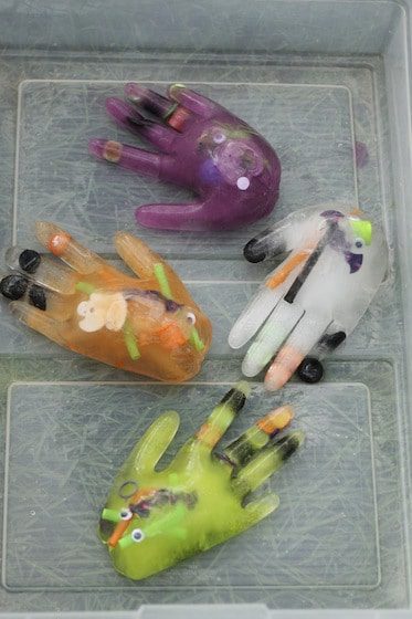 clear plastic gloves filled with plastic halloween toys and frozen water