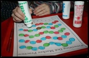 A child using a dot marker to fill in a squiggly line