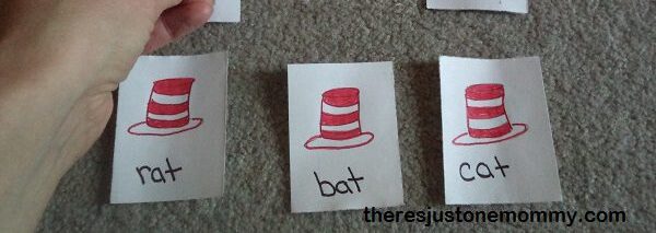 a child's hand holding a card with a red and white striped hat and the word fat other cards below