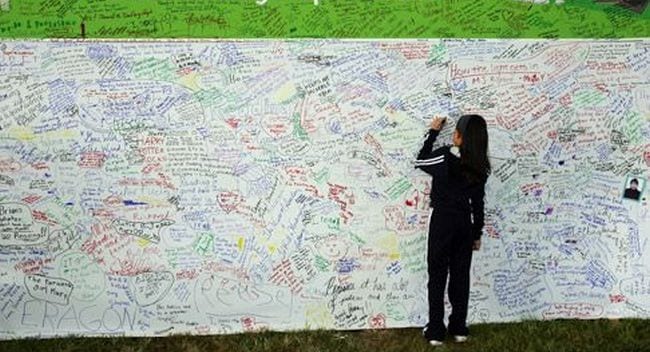 Student writing on a large graffiti wall (End of year assignments)