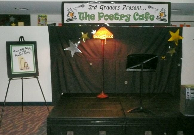Stage with sign saying 3rd Graders Present... The Poetry Cafe (End of Year Assignments)
