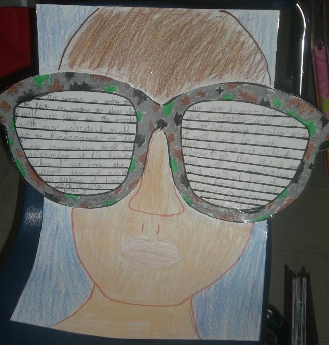 Crayon drawing of student wearing sunglasses, with written end of year assignment on the sunglasses