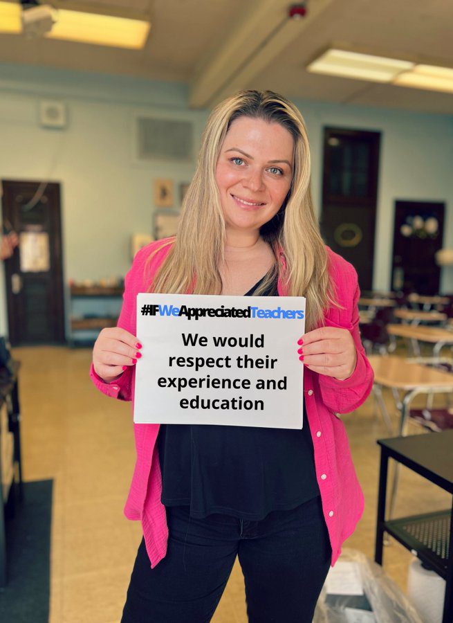 Photo of Dina Lay, teacher, holding sign that reads, "If we appreciated teachers we would respect their experience and education."
