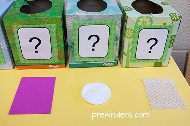 Tissue boxes with large questions marks on them, next to scraps of cloth and a cotton pad