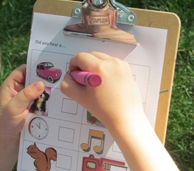 Child holding a clipboard and checking off sounds as they hear them (Five Senses Activities)