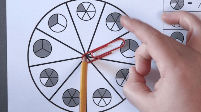 Student spinning a paperclip held in place by a pencil on a circle of fractions