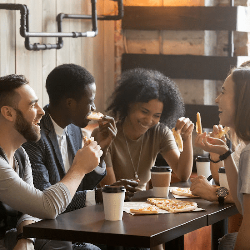 Friends laughing and eating pizza