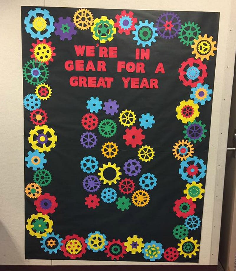 Bulletin board decorated with paper gears, reading 