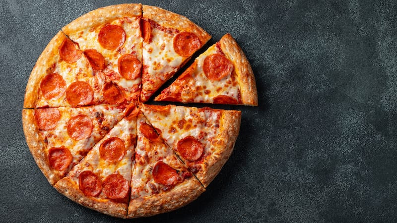 Pepperoni-Pizza auf einer grauen Fläche in 8 Scheiben geschnitten