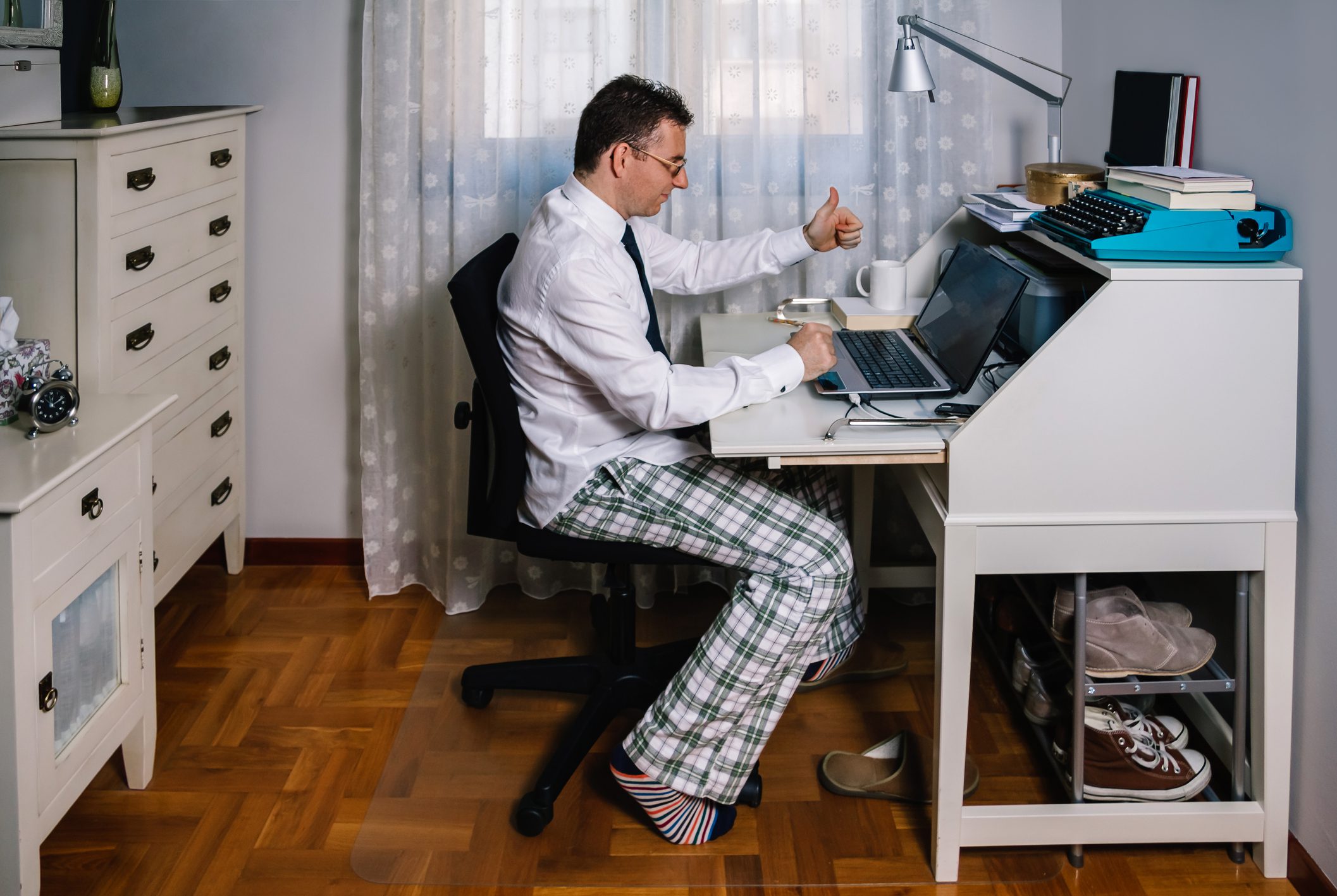 Gömlek, kravat ve pijama pantolon giyen dizüstü bilgisayar ile evden çalışan adam