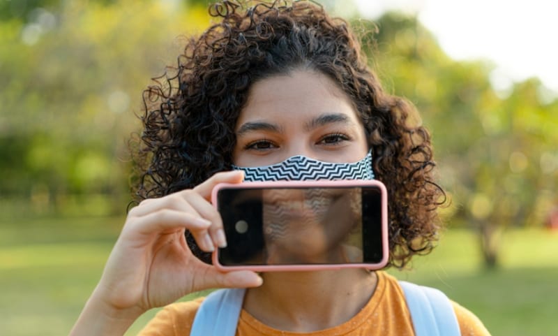 Girl smiling with mask and cell phone
