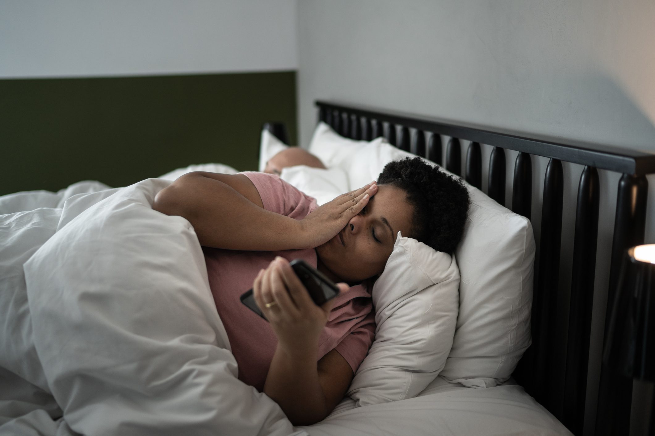 Yatakta akıllı telefonu kontrol eden kadın