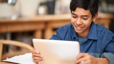 Shot of a young teenage boy using a digital tablet while doing his homework