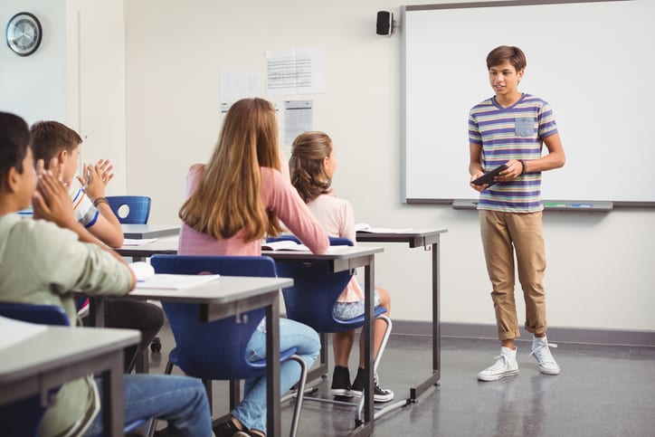 Teenage student presenting to a room of class-mates.