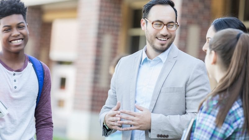 Cheerful high school teacher talks with students
