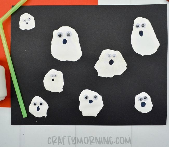 Blow painted white ghosts with googly eyes on black construction paper with green drinking straw