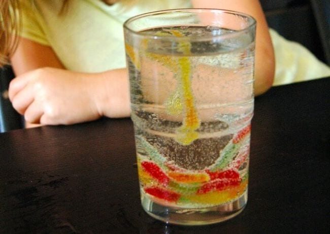 Glass of water with gummy worms floating in it