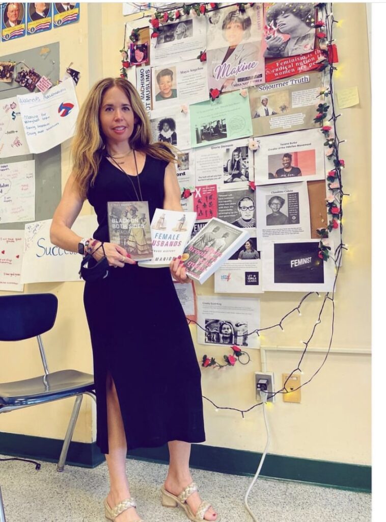 Sari Beth Rosenberg displays important books in front of a bulletin board