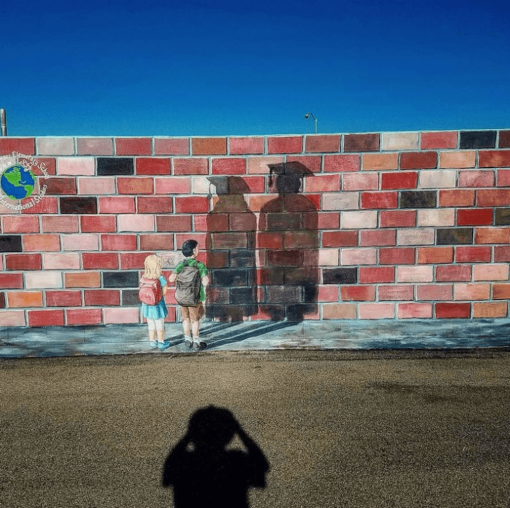 Imagine the future school mural with kids looking at their graduation shadows