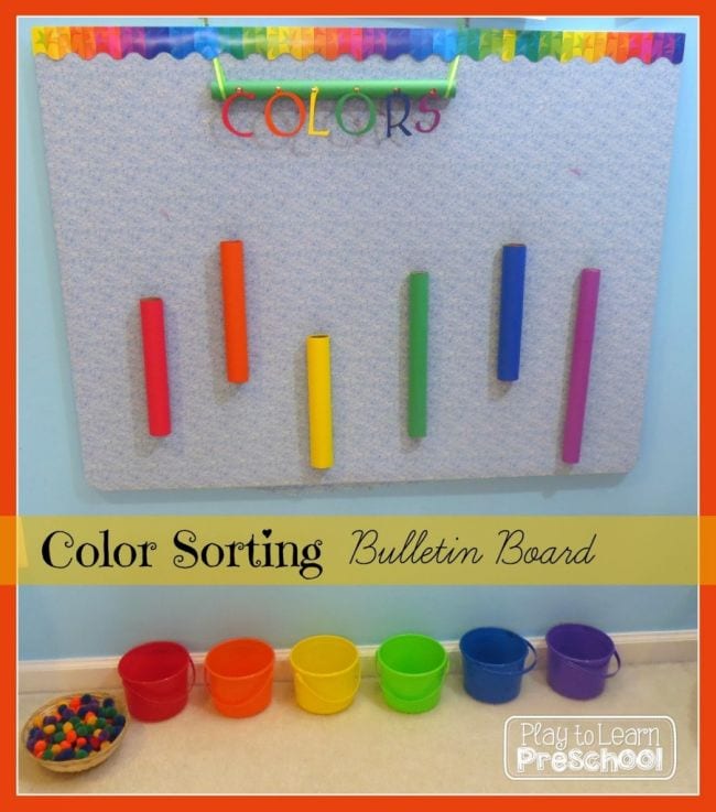 Color sorting bulletin board with colored cardboard tubes and colorful pompoms to drop through into matching buckets