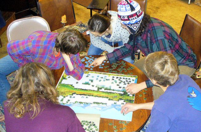 students hunched over a table to put together a puzzle