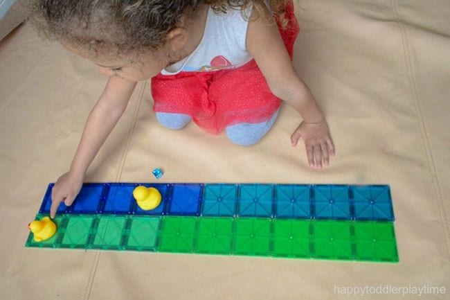 Kindergarten math students moving rubber duck along a line of plastic tiles