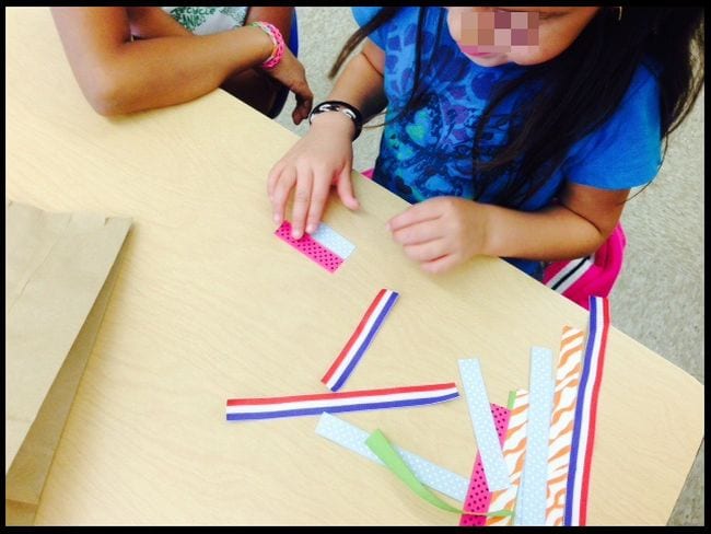 Estudiante de matemáticas de jardín de infancia que compara las longitudes de los trozos de cinta